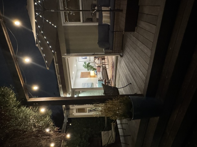 Nighttime patio with warm string lights and open doors to the living room